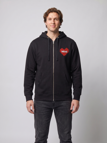 Common Club VeVe Collectors at Heart Zip Up Hoodie — on-model studio fit photo, lean-build man wearing black Independent Trading Co. SS4500Z full-zip hoodie with red VeVe heart chest patch, front view showing relaxed midweight drape, zipped to throat, hood down